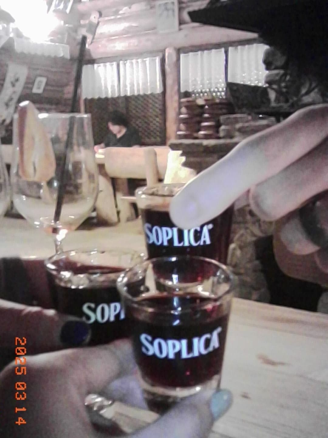 Hands raising small glasses of clear vodka over a restaurant table