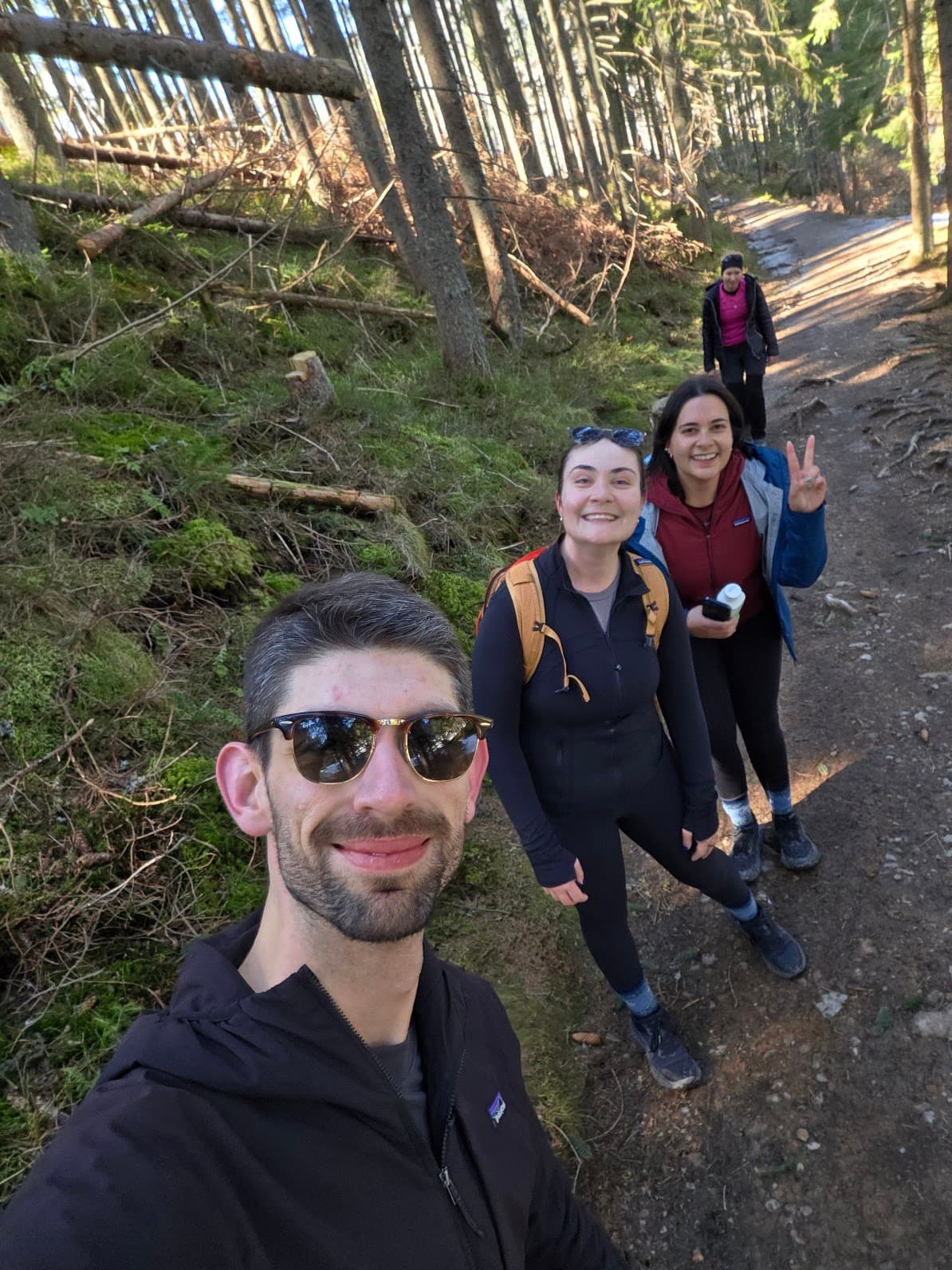 Selfie of three hikers on a snowy trail with mountains behind